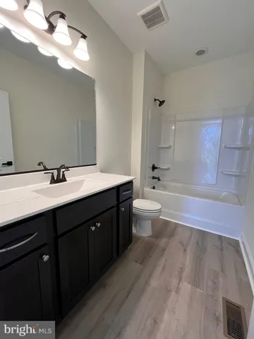 a bathroom with a double vanity sink a toilet and a bathtub