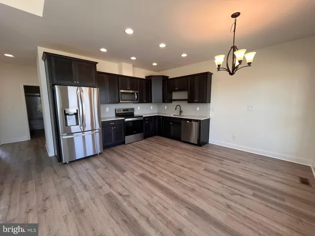 a kitchen with stainless steel appliances granite countertop a refrigerator a oven a sink dishwasher and a microwave with wooden floor