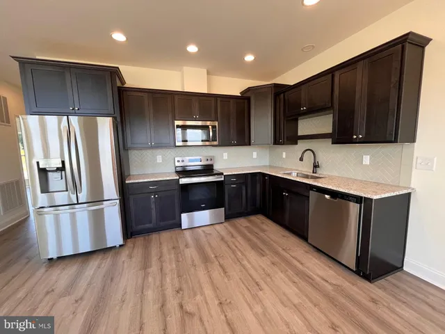 a kitchen with stainless steel appliances kitchen island granite countertop a refrigerator a sink a stove a microwave and cabinets