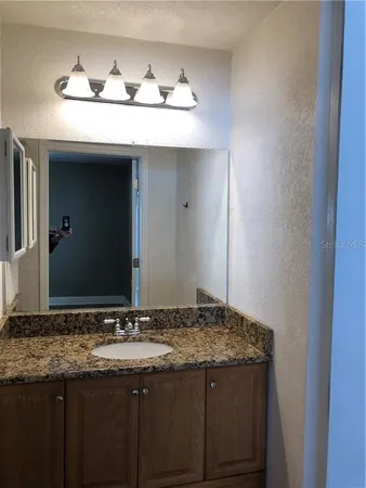 a bathroom with a granite countertop sink and a mirror