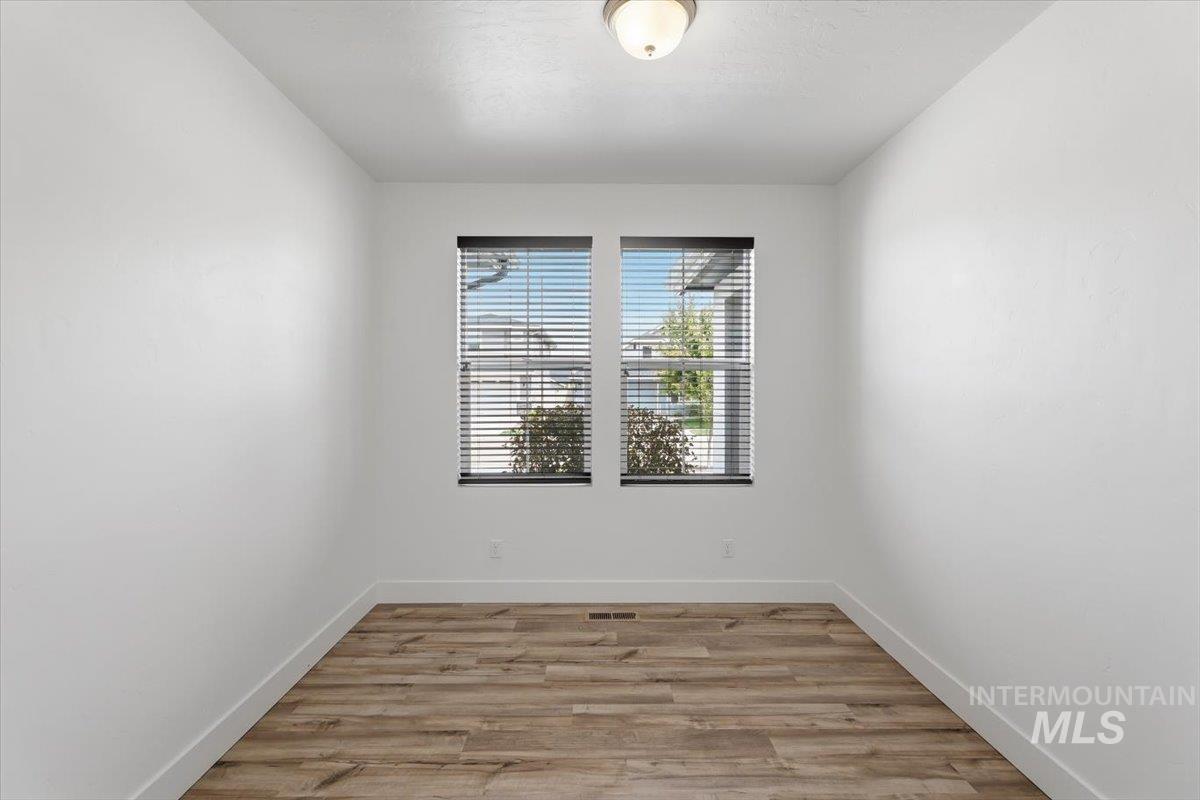 5897 West Riva Capri Street Meridian, ID 83646 - Photo 25 of 50 Room featuring two windows with blinds, wood-finish flooring, white walls, and a ceiling-mounted light fixture