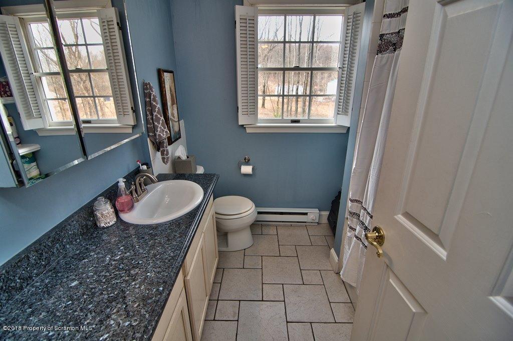 2050 Reservoir Road Moscow, PA 18444 - Photo 38 of 44 a bathroom with a granite countertop sink toilet a mirror and a tub
