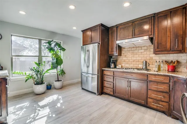 a kitchen with stainless steel appliances granite countertop a refrigerator and a sink