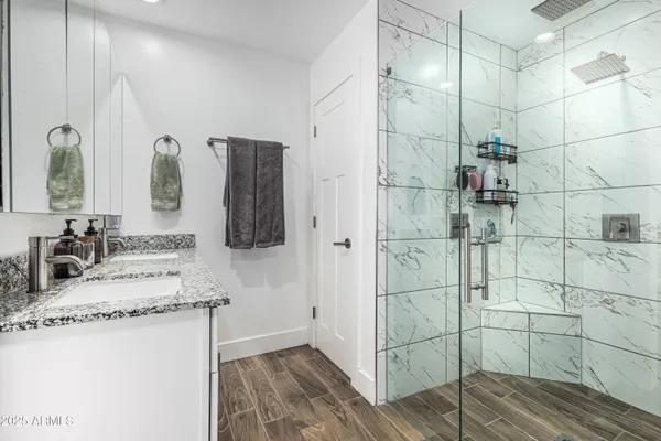 a bathroom with a granite countertop shower a sink and vanity