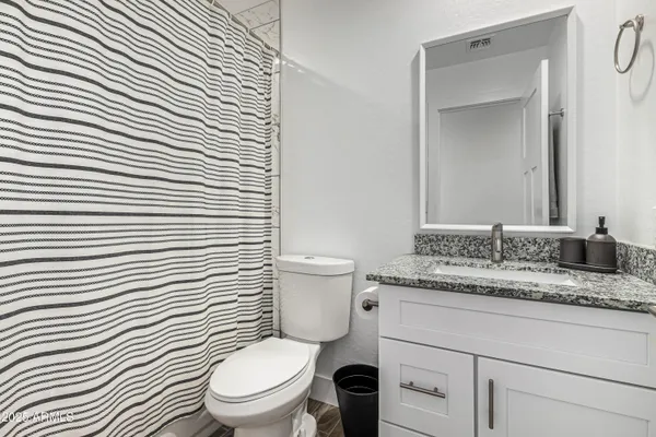 a bathroom with a granite countertop toilet a sink and a mirror