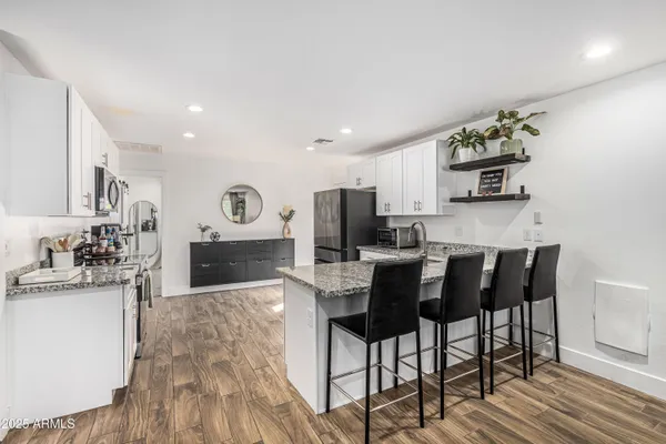 a kitchen with stainless steel appliances granite countertop a stove top oven a sink dishwasher and a dining table with wooden floor