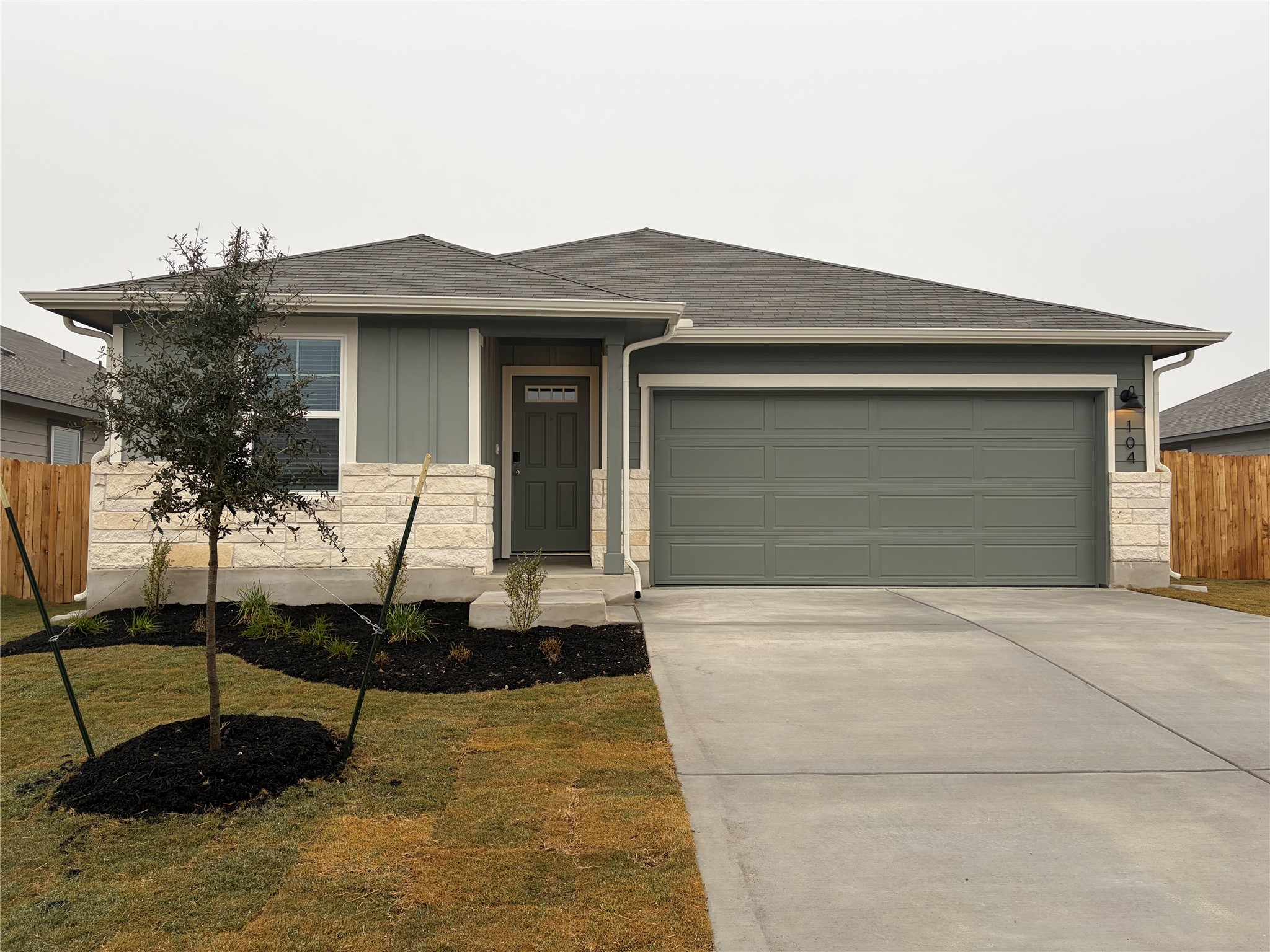 View of front of property featuring concrete driveway, roof with shingles, an attached garage, and board and batten siding