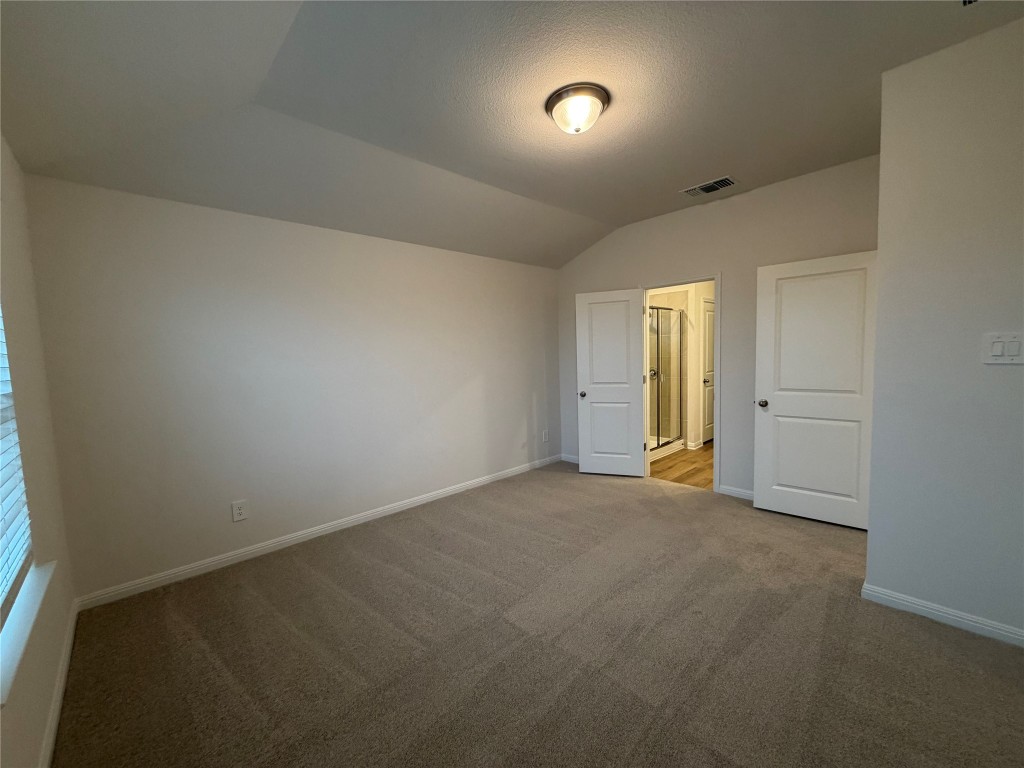 104 Honey Bee Road Jarrell, TX 76537 - Photo 3 of 17 Unfurnished bedroom featuring lofted ceiling, carpet flooring, and a textured ceiling