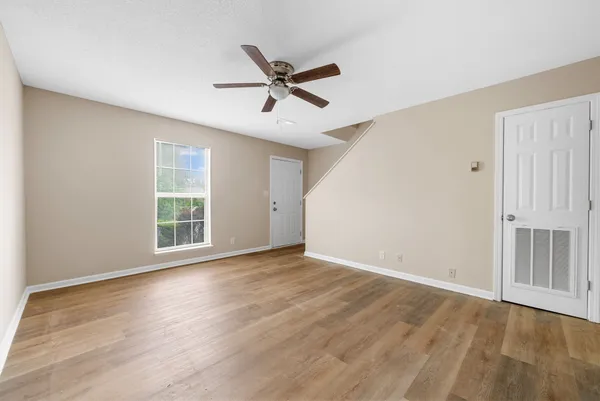 a view of empty room with wooden floor and fan