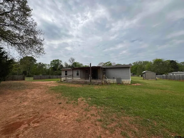 a view of a yard with an house and a car parked in the background