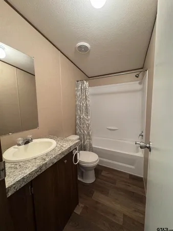 a bathroom with a granite countertop sink toilet and shower