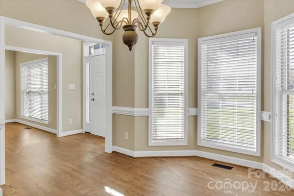 a view of an empty room with wooden floor and windows