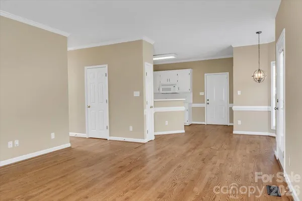 a view of an empty room with wooden floor and a bathroom