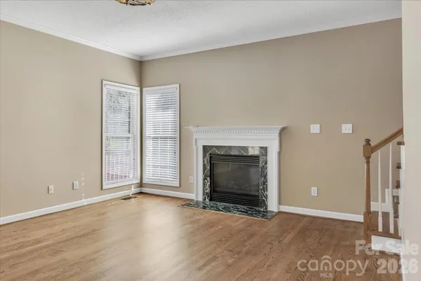an empty room with wooden floor fireplace and windows