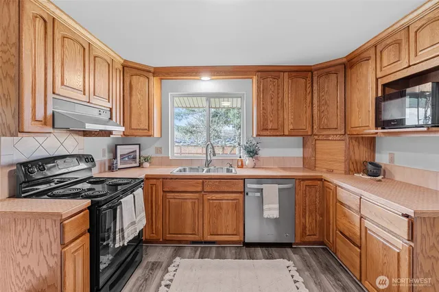 a kitchen with stainless steel appliances granite countertop a stove a sink dishwasher and a microwave oven with cabinets
