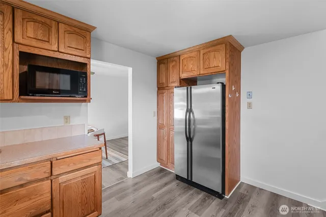 a kitchen with stainless steel appliances granite countertop a refrigerator a microwave oven cabinets and wooden floor