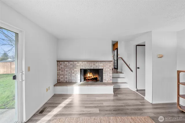 a view of a livingroom with wooden floor and a fireplace