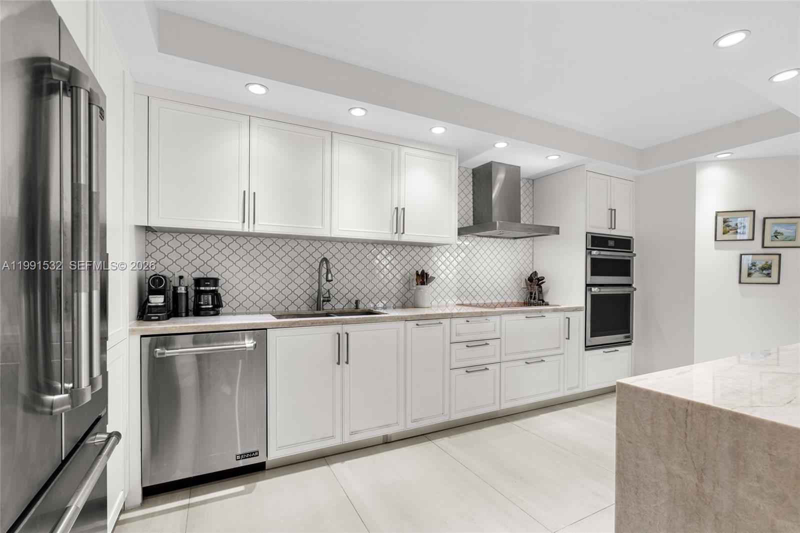 9801 Collins Avenue, Unit 5R Bal Harbour, FL 33154 - Photo 11 of 47 a kitchen with granite countertop white cabinets and stainless steel appliances