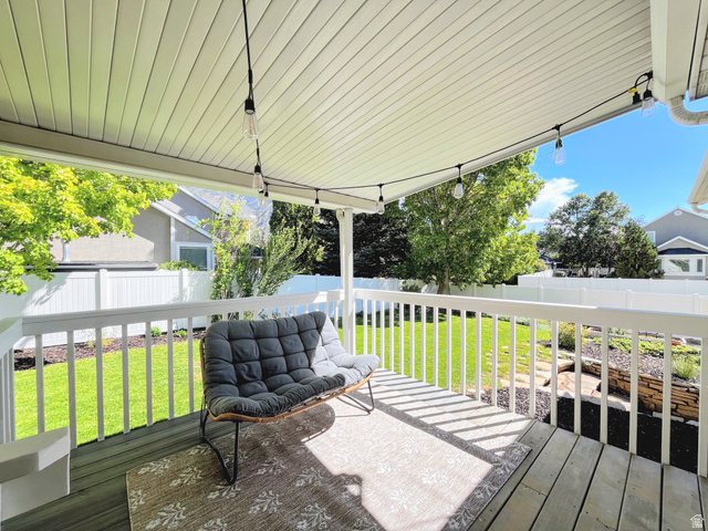 12169 Hidden Valley Road, Unit 44 Sandy, UT 84092 - Photo 36 of 49 Covered patio with wood-finish decking, white railings, and string lighting