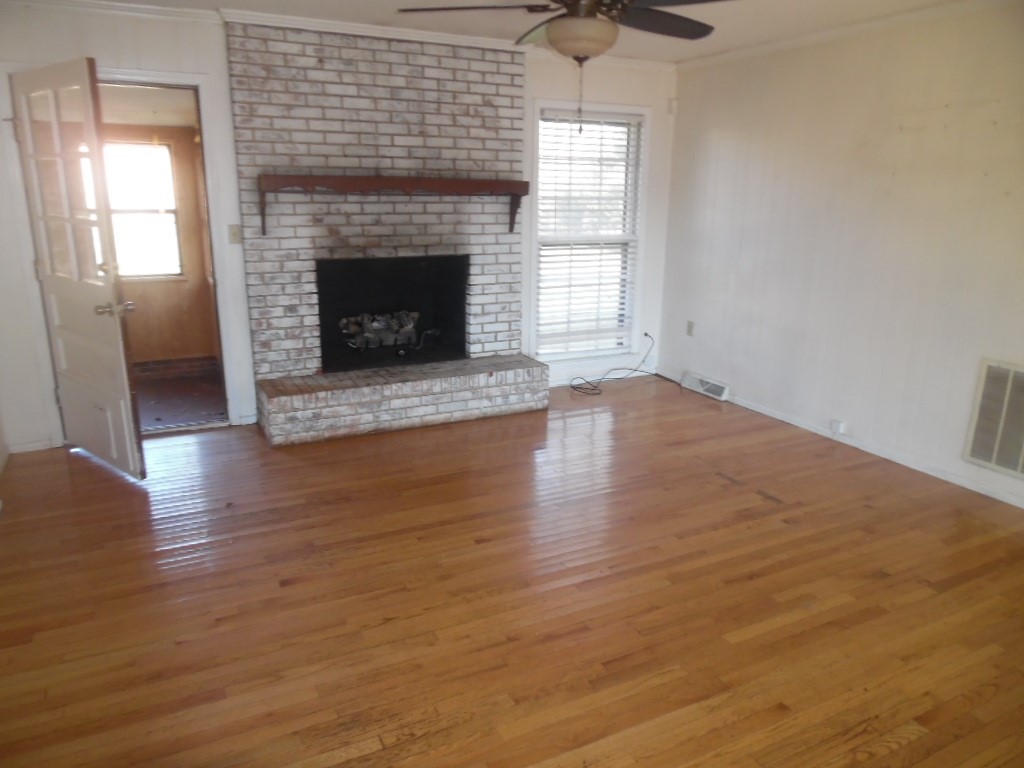 1207 Williamsburg Drive Anderson, SC 29621 - Photo 5 of 13 This sun-drenched living room features rich hardwood flooring and a brick fireplace, creating an inviting ambiance.
