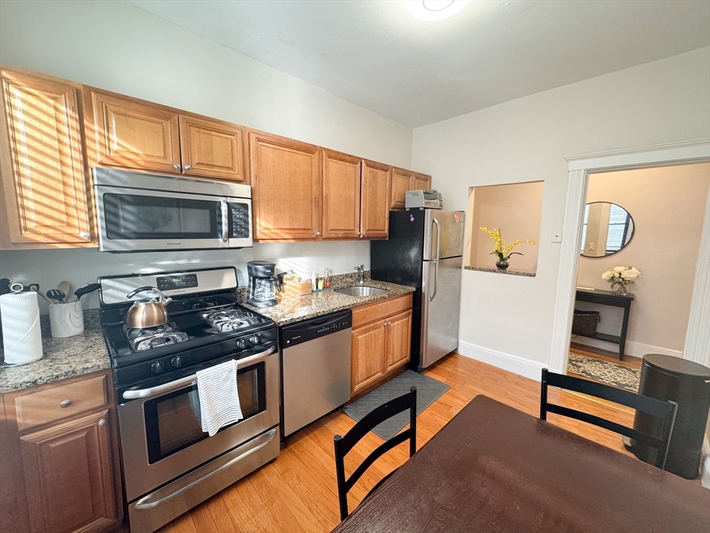 29 Mt Hood Road, Unit 12FURNISHED Boston, MA 02135 - Photo 5 of 11 a kitchen with stainless steel appliances granite countertop a stove a sink and a microwave