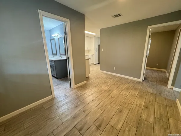 a view of a livingroom with wooden floor and a bathroom