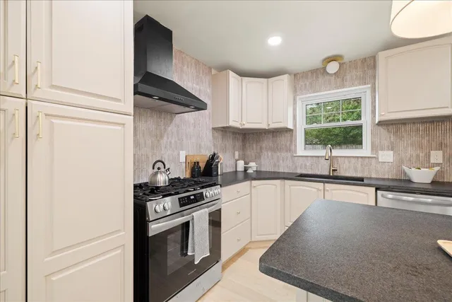 a kitchen with granite countertop a sink stainless steel appliances and cabinets