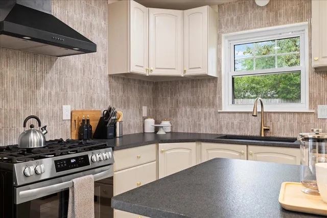 a kitchen with granite countertop a sink a stove and cabinets