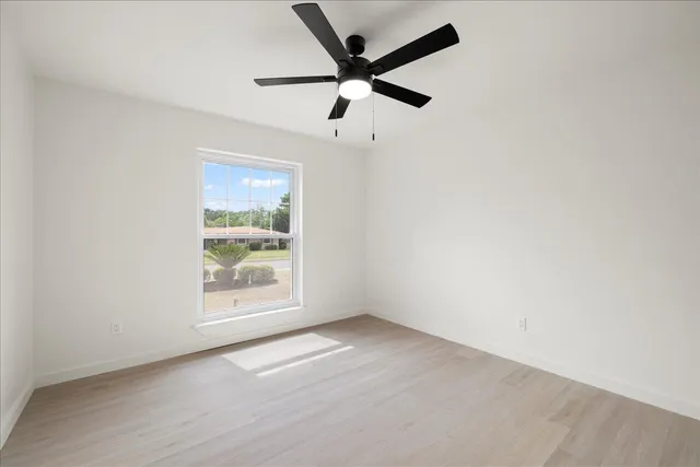 an empty room with a window and a fan