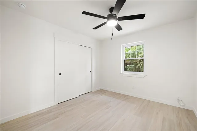 an empty room with ceiling fan and windows