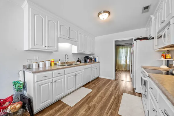 a kitchen with granite countertop white cabinets and white appliances