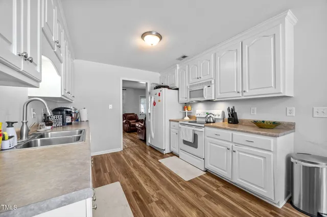 a kitchen with granite countertop a refrigerator sink and white cabinets