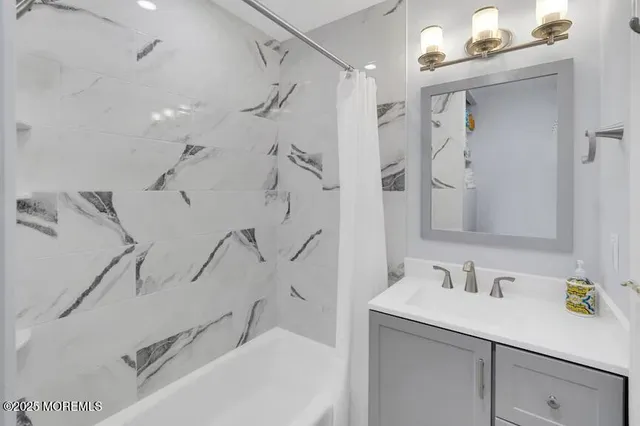 a bathroom with a granite countertop sink mirror and a shower