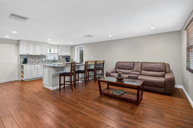 a living room with stainless steel appliances furniture and wooden floor
