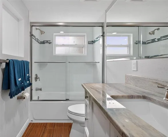 a bathroom with a granite countertop sink toilet and shower