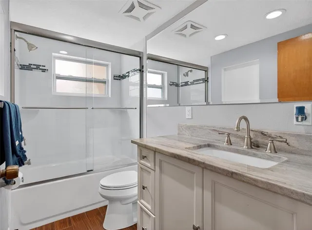a bathroom with a granite countertop sink toilet and shower