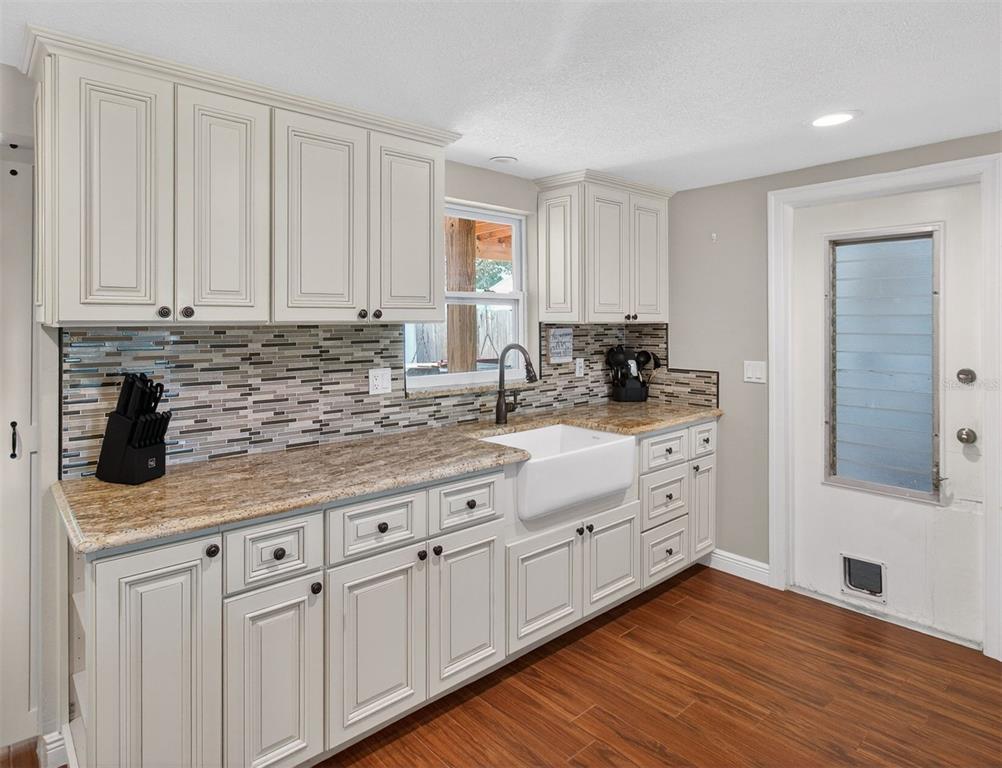 5134 Reseda Drive New Port Richey, FL 34652 - Photo 7 of 37 a kitchen with white cabinets a sink and dishwasher with wooden floor