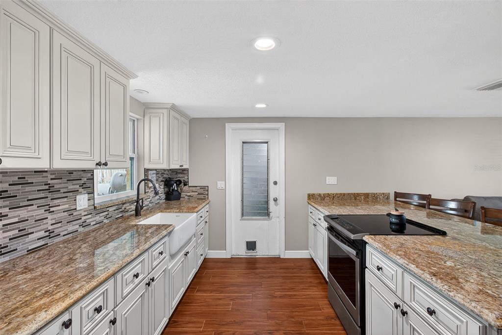 5134 Reseda Drive New Port Richey, FL 34652 - Photo 10 of 37 a kitchen with granite countertop a sink stove and cabinets