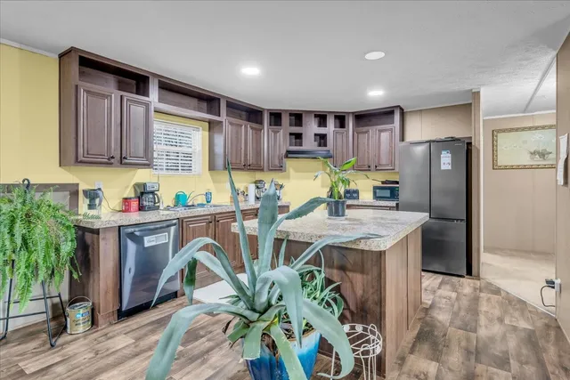 a kitchen with stainless steel appliances granite countertop a refrigerator a sink a stove a dining table and chairs