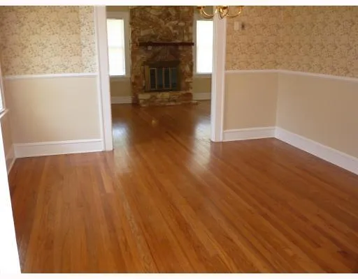 a view of empty room with wooden floor and fireplace