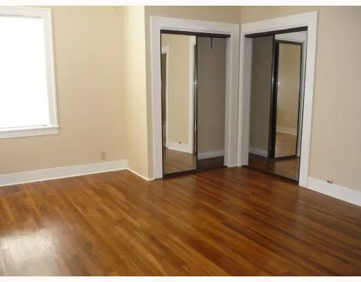 a view of an empty room with wooden floor and closet