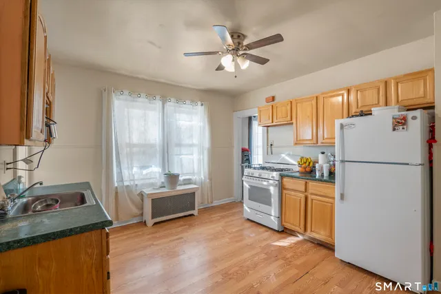 a kitchen with stainless steel appliances granite countertop a refrigerator a sink a stove and a refrigerator