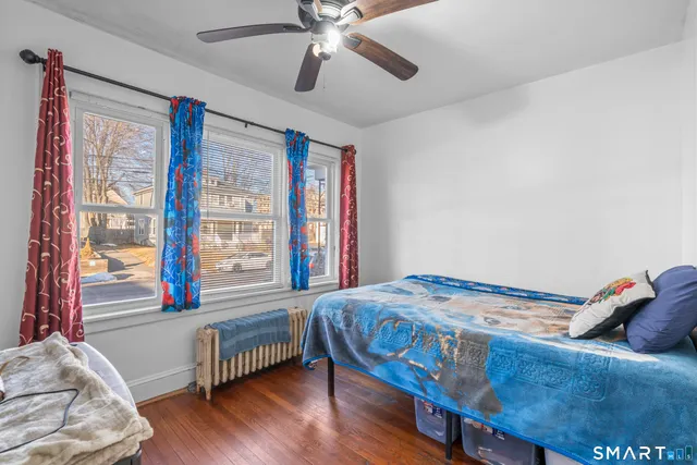 a bedroom with a bed and a large window with wooden floor