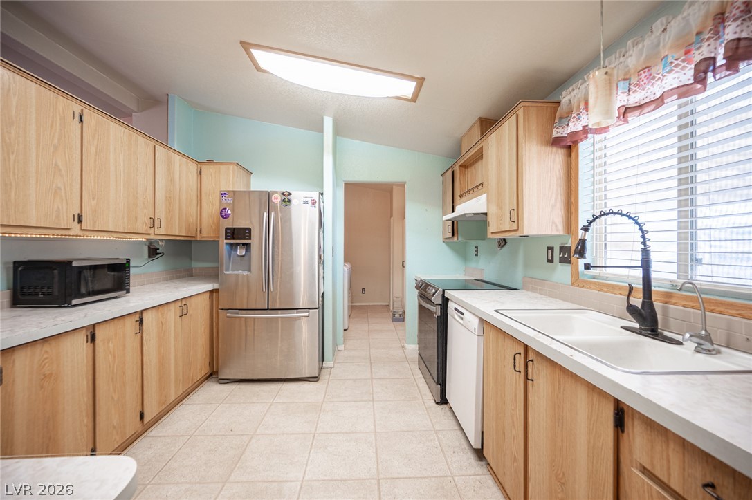 3200 Maple Road Pahrump, NV 89048 - Photo 17 of 53 A galley-style kitchen with natural wood cabinetry and a functional appliance layout.
