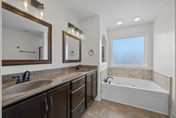 a bathroom with a granite countertop tub sink and mirror