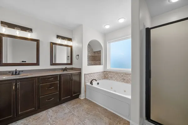 a spacious bathroom with a tub sink and mirror