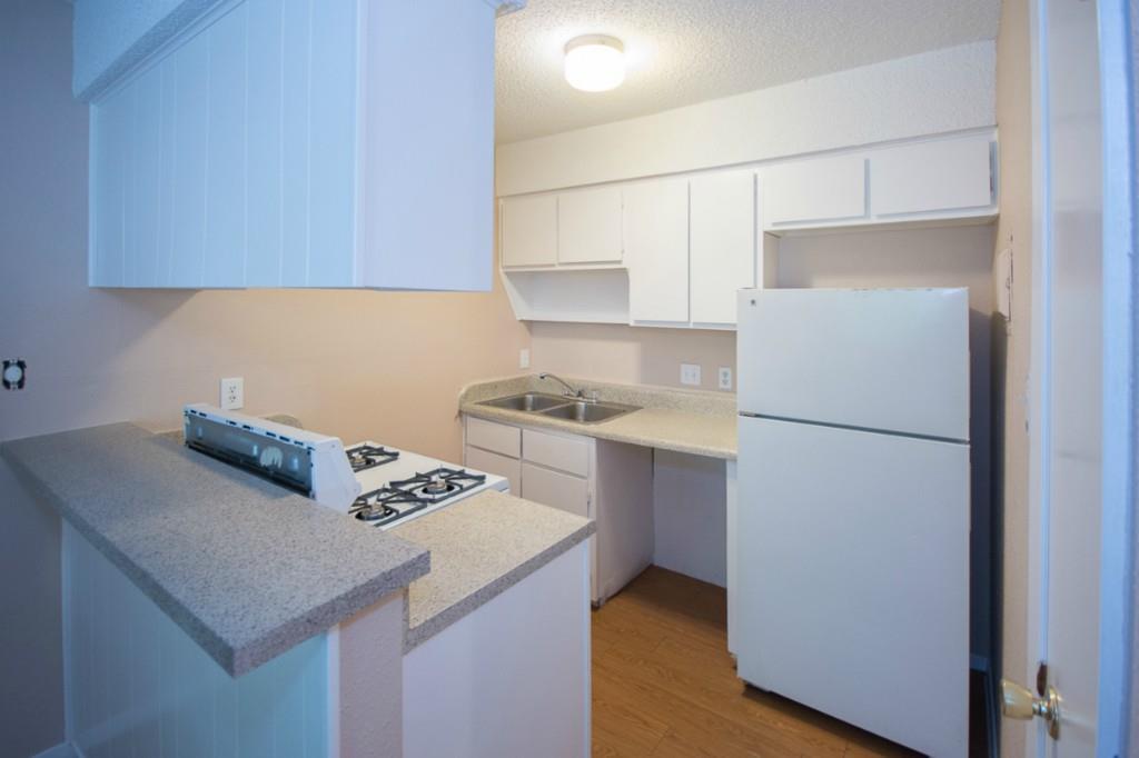 400 West 34th Street, Unit 102 Austin, TX 78705 - Photo 1 of 10 Kitchen with white appliances, white cabinetry, a peninsula, light wood-style flooring, and a textured ceiling