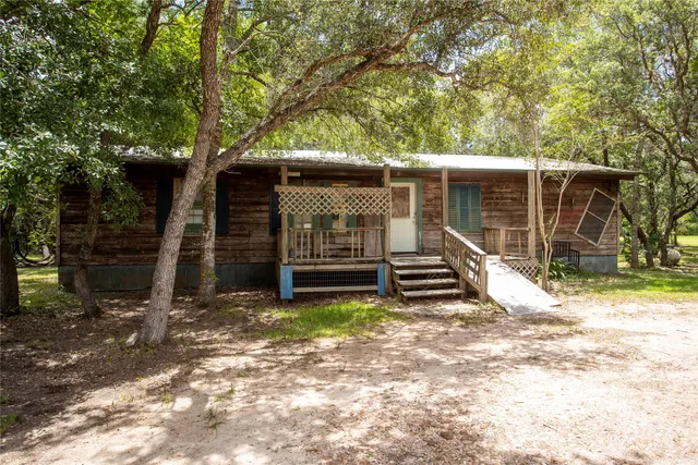 a view of a house with a large tree and a yard