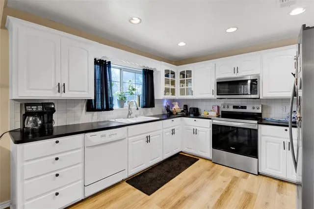a kitchen with granite countertop white cabinets and stainless steel appliances