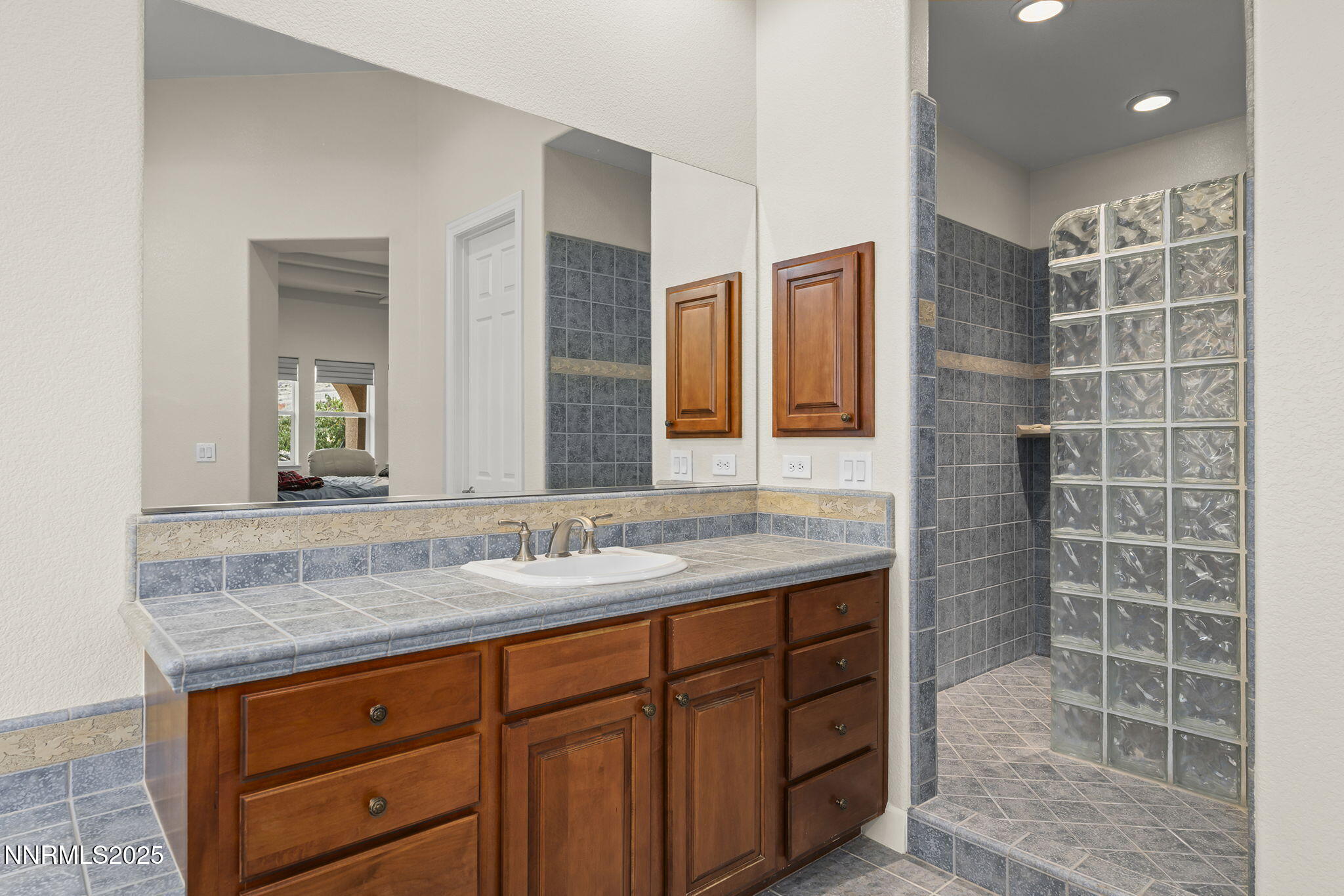 6225 Elk Ivory Drive Reno, NV 89511 - Photo 18 of 44 a bathroom with a granite countertop sink a mirror and a shower